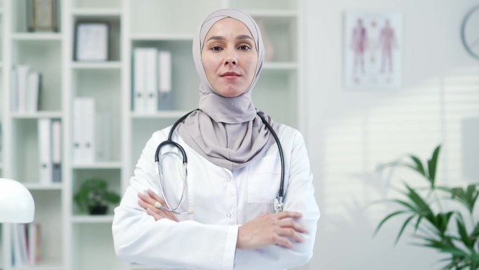 严肃自信的女医生肖像，穿着白大褂，带着听诊器，在现代医院的诊所里看着相机。