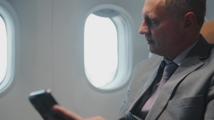 商务旅客乘飞机时使用手机。