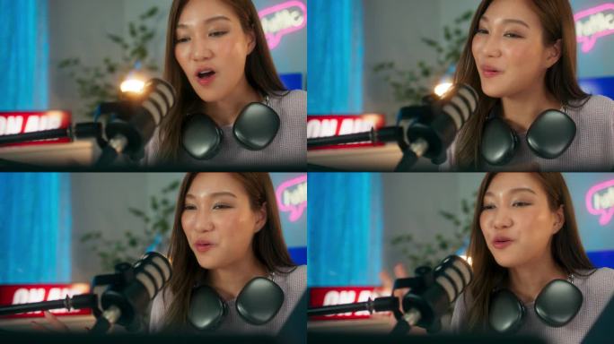 快乐的年轻亚洲女主播带着耳机在电脑上玩在线视频游戏，快乐的年轻女玩家享受着直播