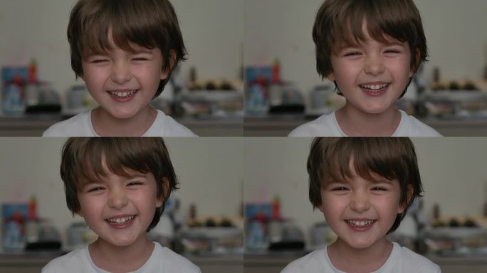 快乐的小孩在笑的特写肖像。小男孩笑在室内特写。小男孩看着镜头微笑的肖像。面对有趣的沉思的孩子。缓慢的