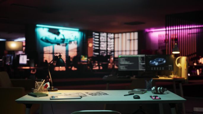 广角拍摄的桌子与智能手机，笔记本电脑和笔记本电脑，放置在一个空的创意办公室在晚上。霓虹灯照亮的现代开