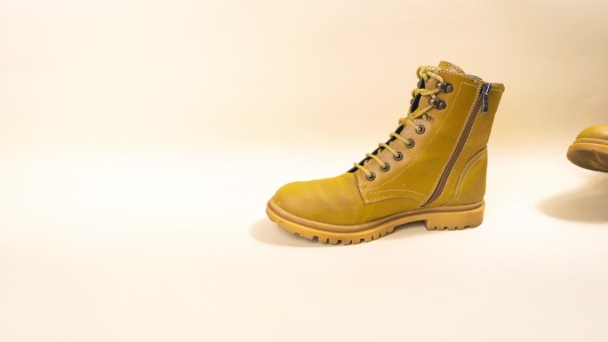黄色的秋靴踩在米色的背景上。秋天来临的概念。秋季降温。
