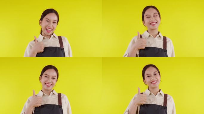 年轻的亚洲咖啡师女士穿着围裙站着，微笑着兴奋地竖起大拇指，黄色背景，服务员或企业家愉快，小企业或创业