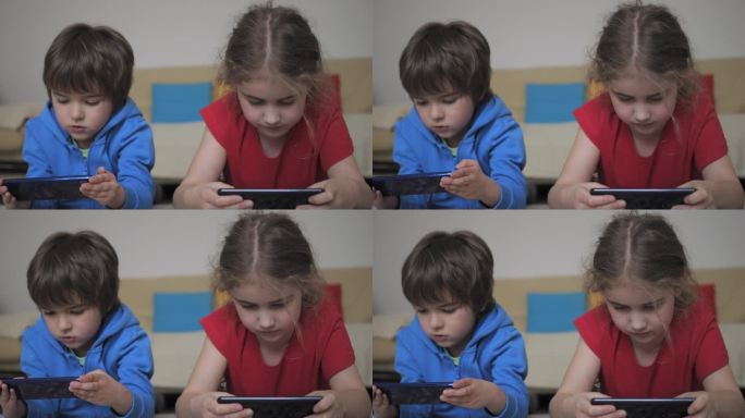 孩子们躺在地板上玩手机。孩子们在手机上玩电子游戏。男孩和女孩玩电子游戏智能手机。朋友用手机玩游戏、在