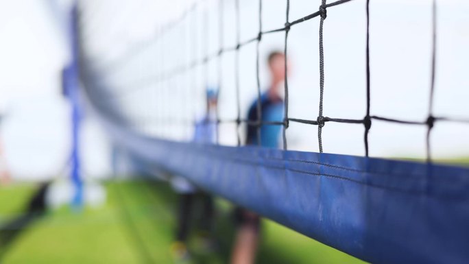 排球比赛，初中十几岁的校队的孩子们打排球，队员们在室外操场上用网子和绿油油的草坪球场上运动，儿童队在