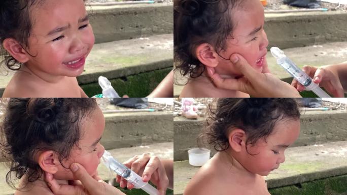 一位亚洲母亲正在帮她的小女儿用盐水冲洗鼻腔