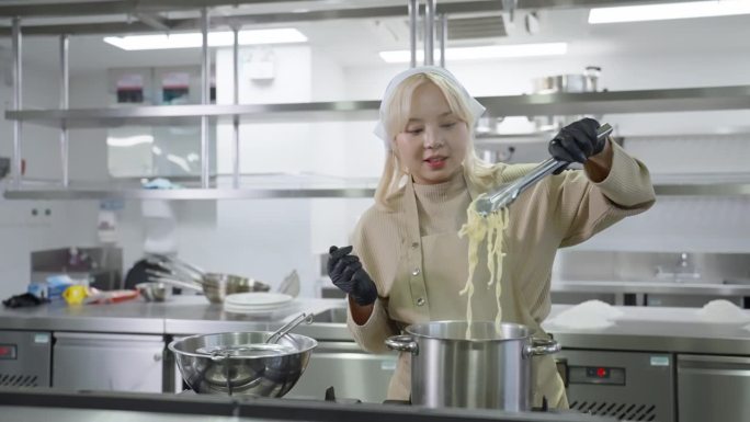 亚洲中国职业女学生，穿着烹饪服，系着围裙，用沸水锅煮黄面条或意大利面。在商业餐厅清洁厨房工作的高技能