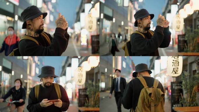 亚洲大胡子男子在街边夜市用智能手机拍照。