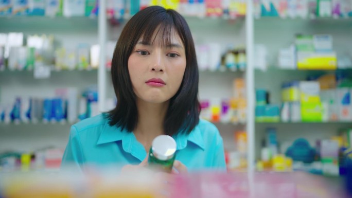 年轻的亚洲妇女在药店找药。