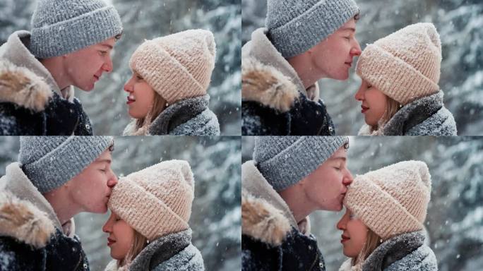 冬天，年轻的情侣在飘落的雪中拥抱亲吻的特写。