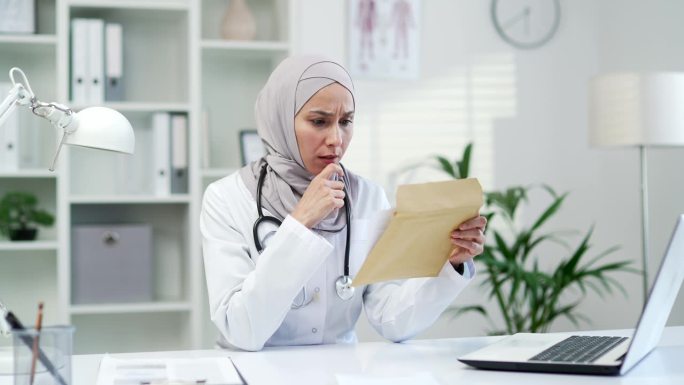 悲伤的穆斯林女医生坐在医院诊所的办公室里收到了噩耗的信