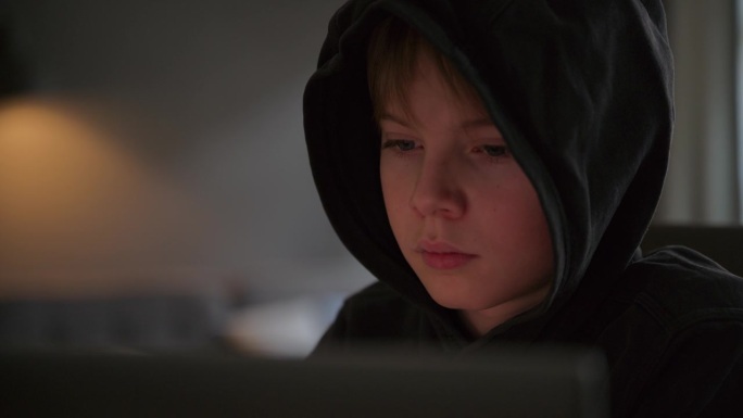 穿着连帽衫的男孩坐在电脑前