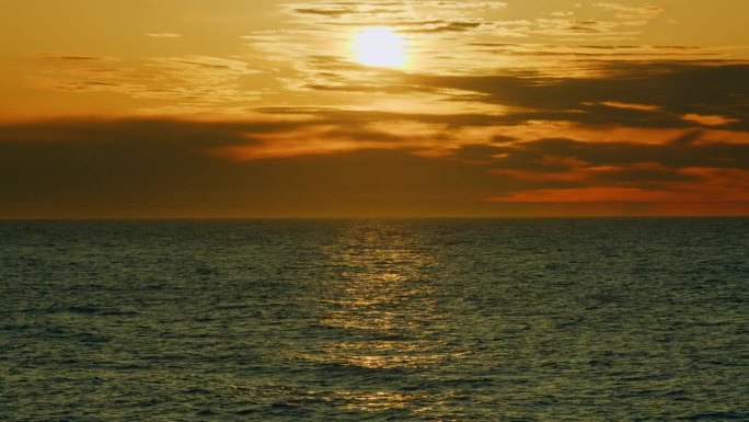 自然的概念。金色之光的海洋全景。太阳升起在海洋和红色的天空，看到海浪。真正的时间。
