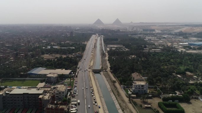 航拍:在吉萨的埃及金字塔的背景中，尼罗河的一个分支在前景中，Maryotya分支沿着尼罗河的源头而来