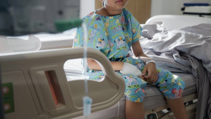 一个心烦意乱的男孩独自坐在医院的病床上，因为他得了流感。