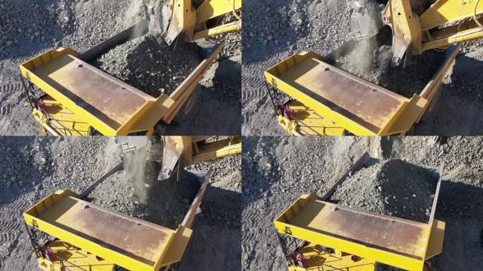 在碎石采石场，挖掘机将碎石装入自卸卡车，慢动作