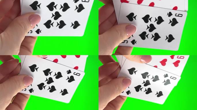 手拿着四个九在绿色背景的特写女性的手与法式美甲。女人整理卡片，检查它们折叠起来，像扇子一样展开同一套