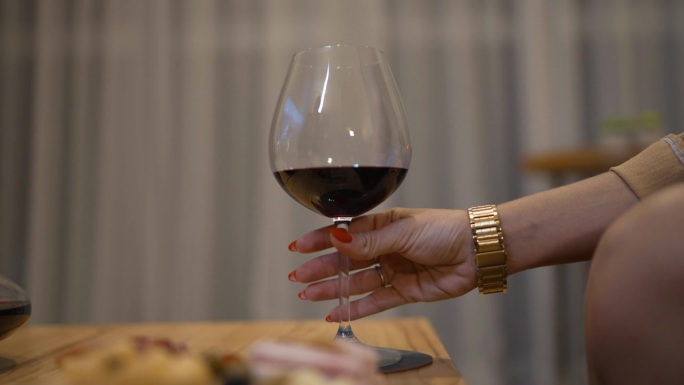 女性的双手优雅地举起酒杯敬酒，捕捉到品味一杯美酒的精致和享受。