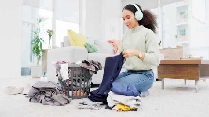 清洁，房子和女人在客厅地板上或管家叠衣服，春季大扫除和戴耳机听。洗衣服和叠衣服在家里或工作的人与音乐