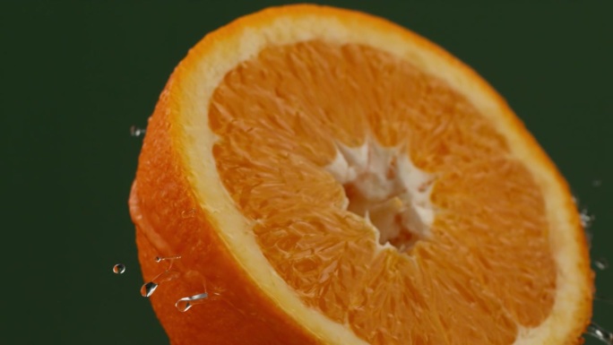 用慢动作旋转一个湿漉漉的橙子。飞溅的水滴