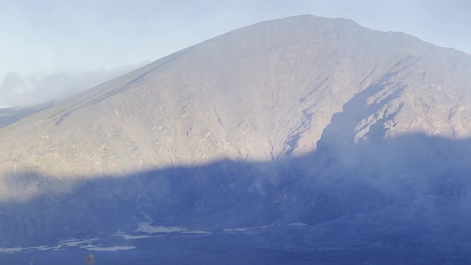 电影镜头从入侵的菠萝洋甘菊植物到夏威夷毛伊岛被云层覆盖的哈雷阿卡拉火山口。30fps的4K HDR