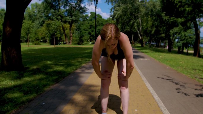 疲惫健康的女性跑步者筋疲力尽的有氧运动和呼吸困难的户外