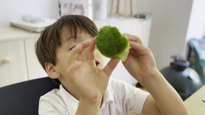 有条理的小男孩小心地从碗里挑选花椰菜，边吃边检查