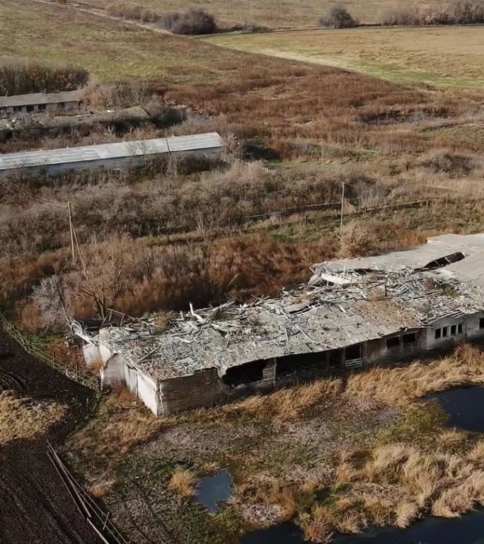 垂直航拍被摧毁的农场，有牛棚和有弹坑的谷仓，真实的乌克兰战争