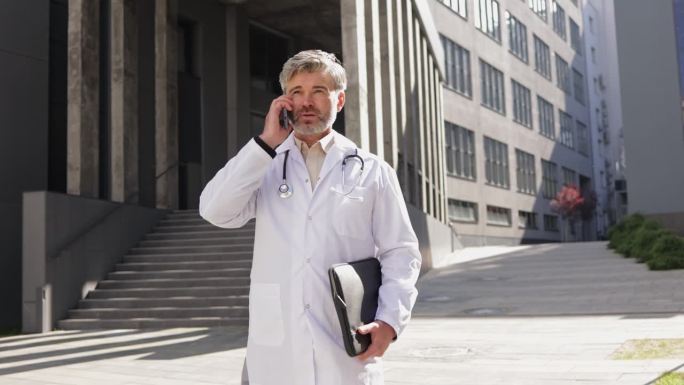 男医生用手机向病人问诊，走到户外。