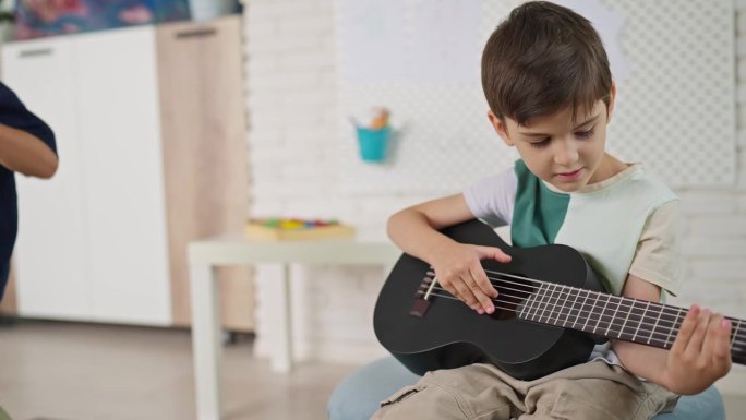 小男孩在家里弹吉他