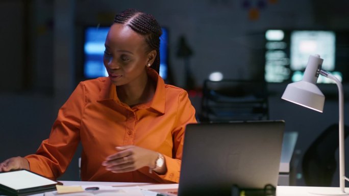 笔记本电脑，平板电脑和一位黑人商务女性在她的办公室里做计划，研究或写作。科技，微笑和黑暗与一个快乐的