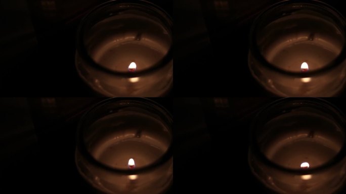 在透明的罐子里摇曳的蜡烛火焰特写-高角度拍摄。火焰在蜡烛上燃烧的特写，孤立在黑色背景上。黑暗中的烛光