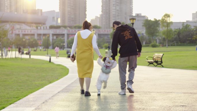 幸福的一家三口  父母牵着孩子学习走路