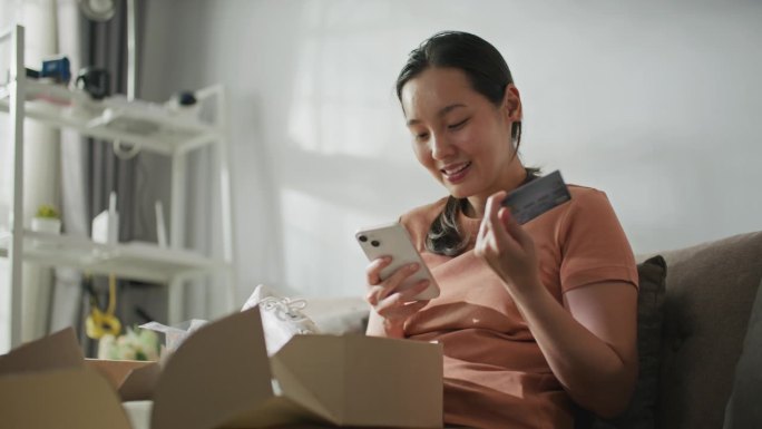 快乐的亚洲女性在家里用智能手机网购
