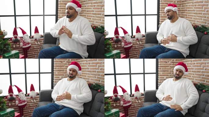 一个非洲裔美国人在家里戴着圣诞帽忍受着胃痛