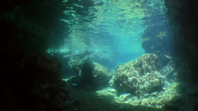 摄像机通过水下隧道移动到石头上方的太阳光线。