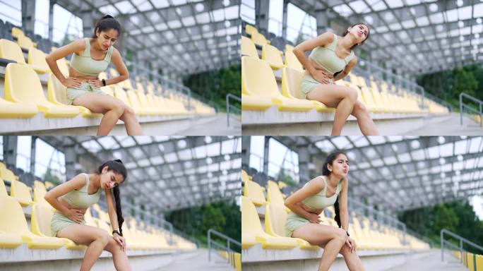 年轻的印度运动女子坐在城市体育场时胃痛