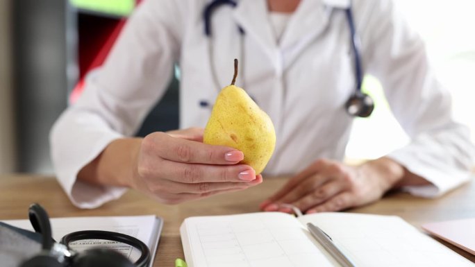 女医生坐在桌边给病人吃鲜梨