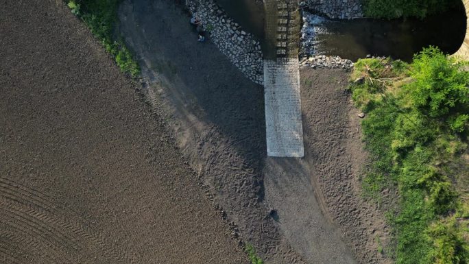 这条土路穿过一条小溪，这条小溪穿过河流，在洪水无法通行时继续前进。修复河道，将农田垂直排水改道