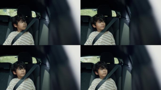 一个可爱的男孩正在汽车后座上放松。在通往山区乡村的路上看着窗外