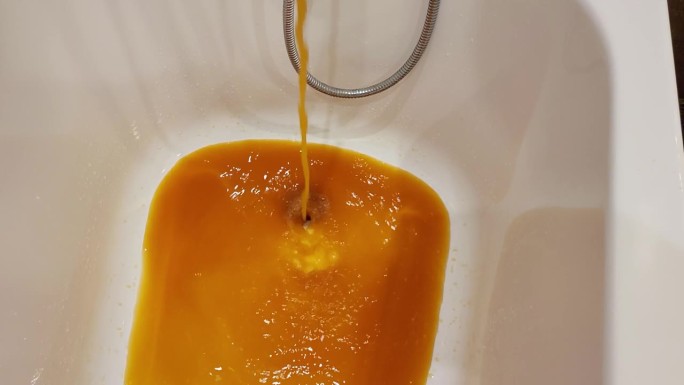 浴室里的水龙头正在流出棕色的脏水，这些水被管道上的铁锈污染了。