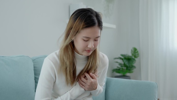 手握胸脯有心脏病发作的症状，亚洲女性辛苦工作时有胸痛引起的心脏病，漏、扩张、冠状动脉增大，按压胸部有