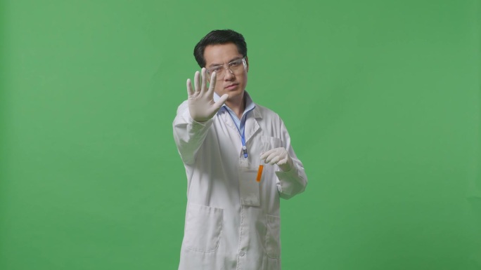 亚洲男性科学家用橙色液体试管看着镜头，在实验室的绿色屏幕背景上没有手势表示不赞成
