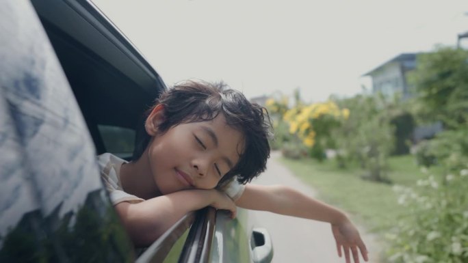 可爱的小男孩伸出车窗和你的父母一起在旅途中感到快乐和放松。