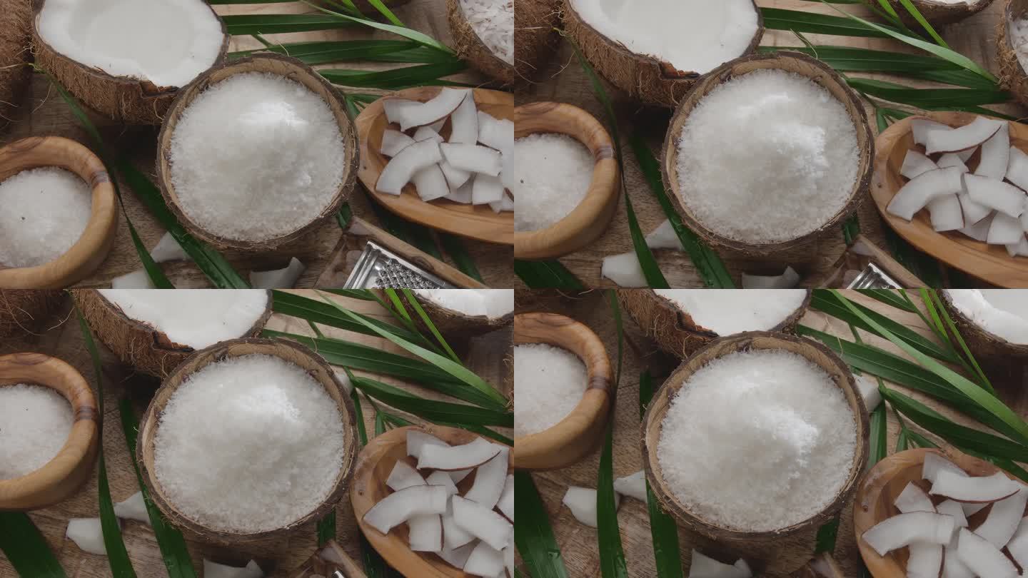 新鲜打开的椰子和椰子片、椰子片、椰子叶一起在木桌上慢慢旋转。