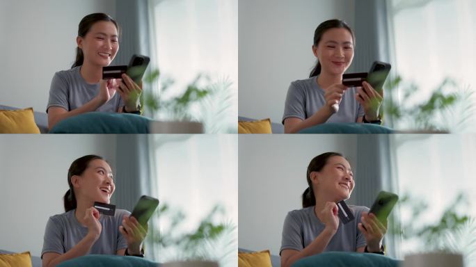 亚洲女人开心地微笑着坐在沙发上，用智能手机和信用卡在家里网上购物。