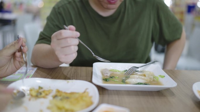 周末，一个胖乎乎的男人在泰国街头小吃摊吃饭，吃着浓汁炒米粉，而他的朋友们正在吃其他泰国菜。