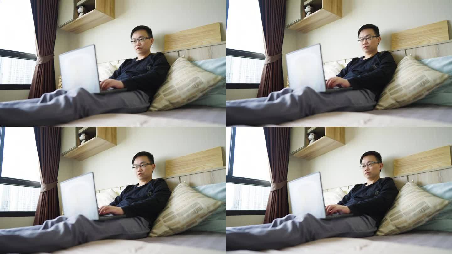 男人躺在床上用笔记本电脑工作
