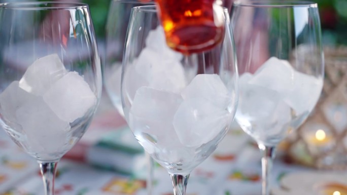 传统意大利aperol sprice的制作过程，在露天的朋友聚会上，调酒师将aperol倒入装有冰块