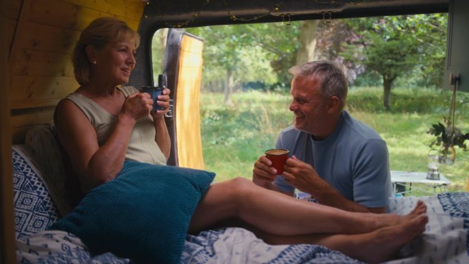 老夫妇在乡村露营，一起在房车里喝咖啡，放松心情